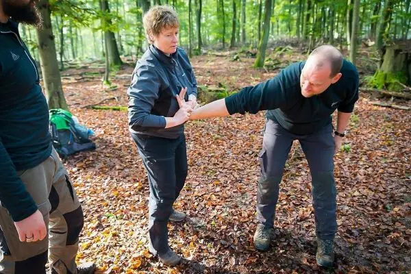 Eine Person demonstriert eine Technik zur Handbefreiung im Wald