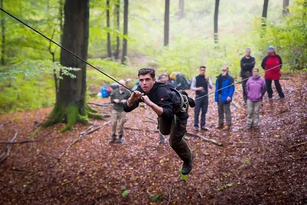 Junge überquert eine selbstgebaute Seilbrücke im Wald