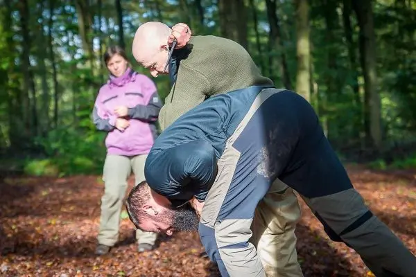 Kampftechniken werden im Wald geübt, eine Person wird kontrolliert gehalten