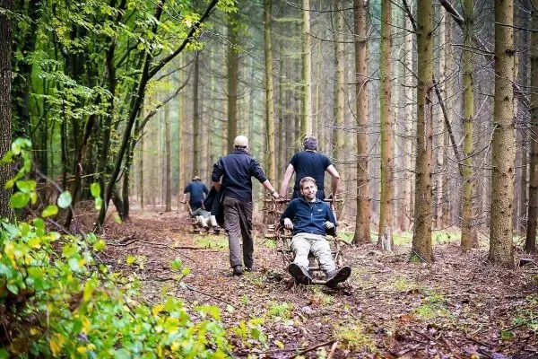 Männer ziehen improvisierte Trage durch den Wald zwischen Bäumen