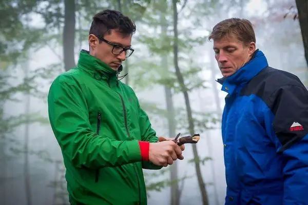 Mann bearbeitet Holzstück mit einem Messer im Wald