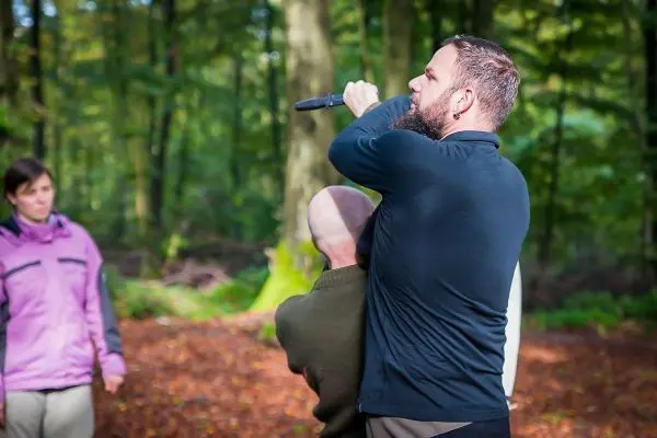 Mann demonstriert eine Technik mit einem Messer im Wald
