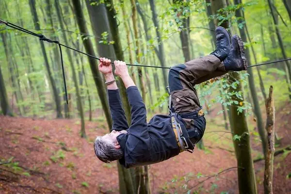 Mann überquert eine selbstgebaute Seilbrücke im Wald