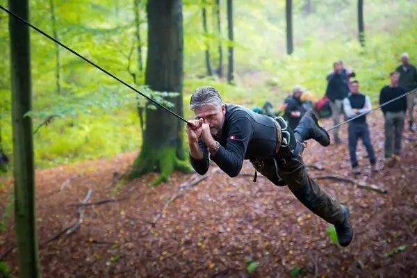 Mann überquert selbstgebaute Seilbrücke im Wald