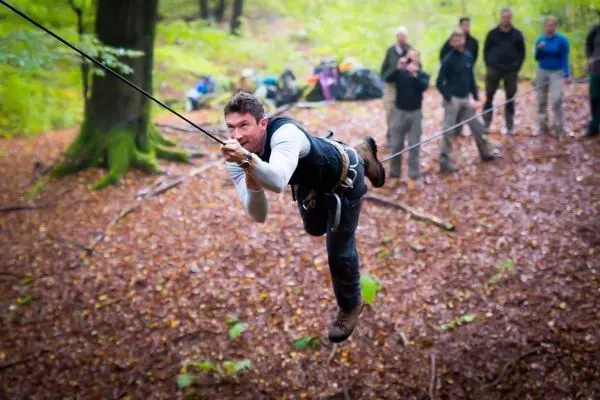 Mann überquert selbstgebaute Seilbrücke in einem Waldgebiet