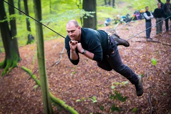 Mann überquert selbstgebaute Seilbrücke zwischen Bäumen im Wald