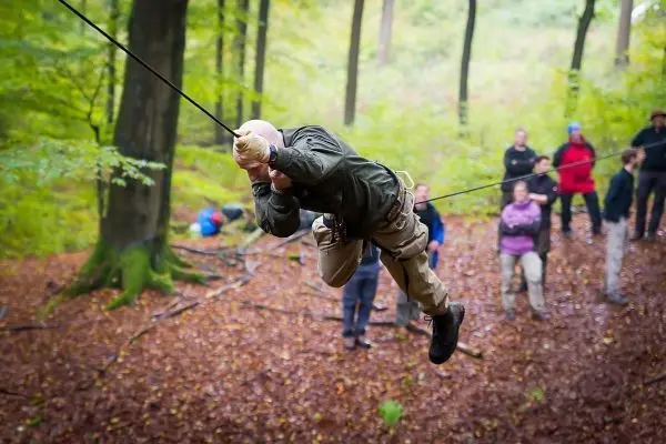 Mann überquert selbstgebaute Seilbrücke zwischen Bäumen im Wald