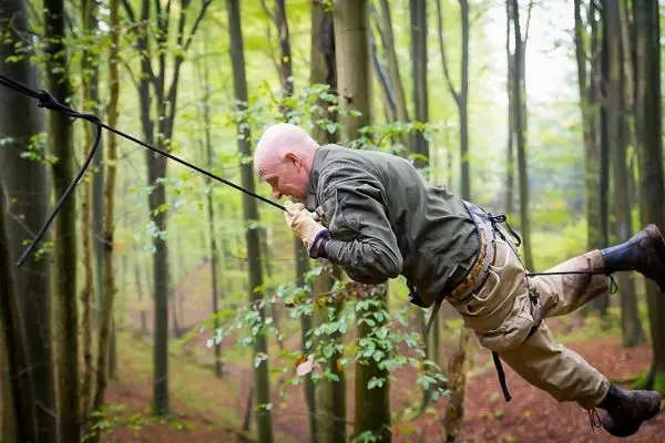 Mann überquert selbstgebaute Seilbrücke zwischen Bäumen im Wald