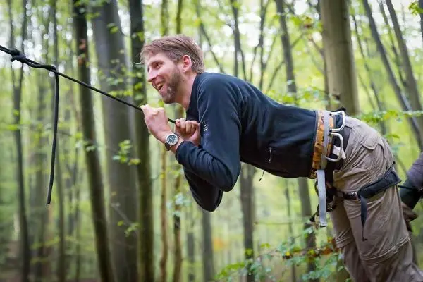 Mann zieht sich an einem Seil in einem Wald hoch