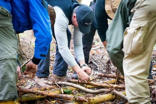 Mehrere Personen sammeln Äste und Zweige auf dem Boden