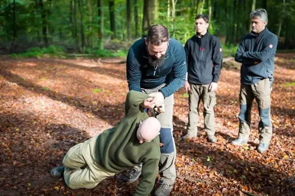 Person demonstriert eine Technik zur Kontrolle einer anderen Person im Wald