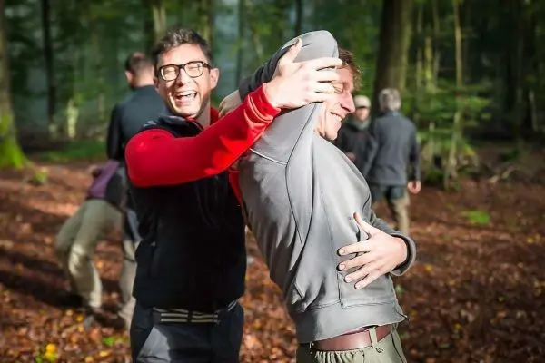 Person hält andere Person fest und lächelt dabei im Wald