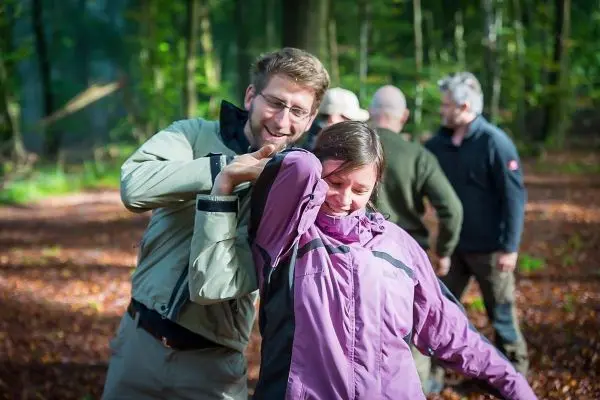 Person hilft anderer Person beim Üben einer Technik im Wald