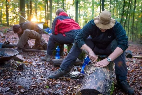 Person schnitzt an einem Holzstück im Wald