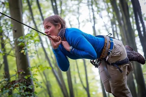 Person schwingt an einem Seil zwischen Bäumen