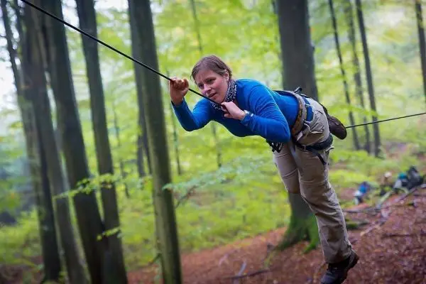 Person schwingt an einem Seil zwischen Bäumen