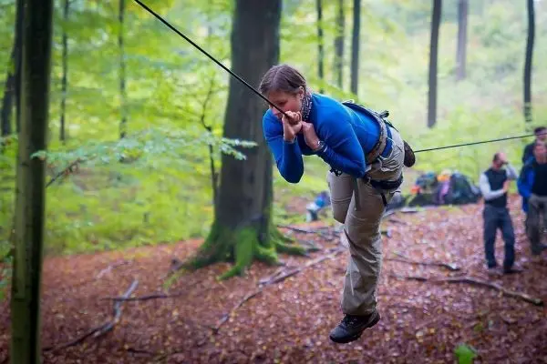 Person schwingt an einem Seil zwischen Bäumen im Wald