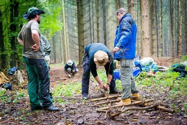Personen bauen eine Struktur aus Ästen im Wald beim Survival Training