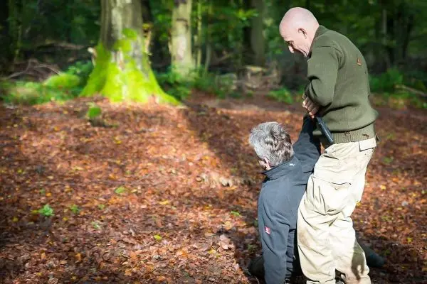 Zwei Personen im Wald, eine Person hält die andere am Kragen
