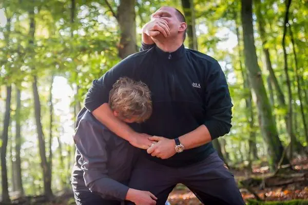 Zwei Personen üben eine Selbstverteidigungstechnik im Wald aus