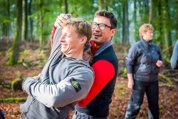 Zwei Personen üben eine Technik im Wald, eine Person hält die andere