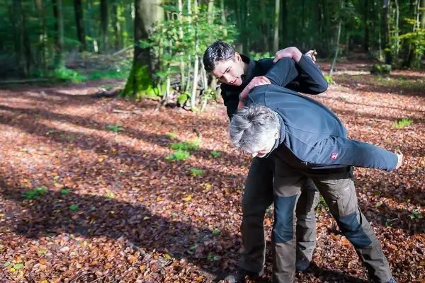 Zwei Personen üben eine Technik zur Kontrolle im Laubwald aus