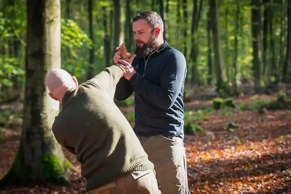 Zwei Personen üben eine Technik zur Selbstverteidigung im Wald