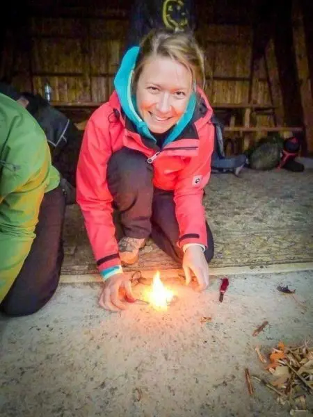 Kleine Flamme brennt auf dem Boden, Person hält die Hände daneben