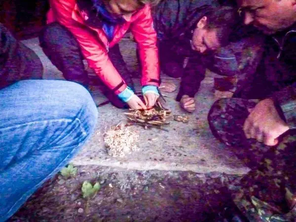 Person bereitet Feuerstelle mit Holz und Zunder vor beim Survival Training