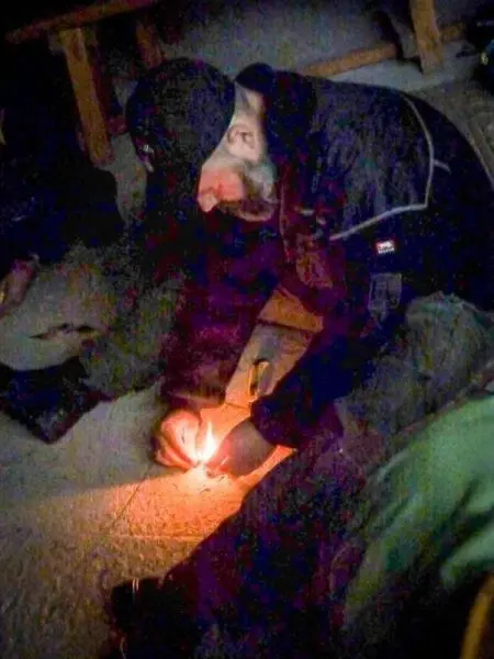 Person entzündet Feuer mit Zunder auf dem Boden beim Survival Training