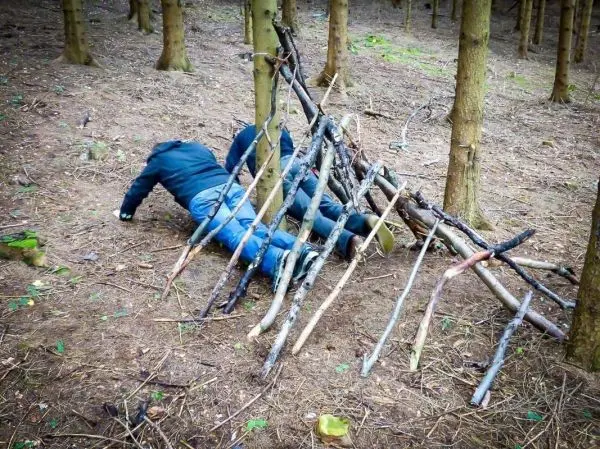 Selbstgebaute Konstruktion aus Ästen dient als Hindernis für Kriechübung