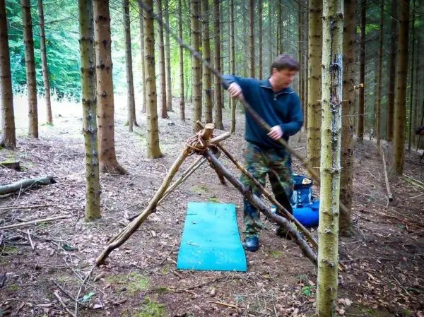 Selbstgebaute Konstruktion aus Ästen wird auf einer blauen Unterlage stabilisiert