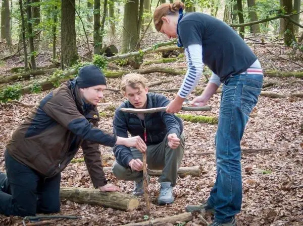 Drei Personen arbeiten an einer selbstgebauten Schlagfalle im Wald