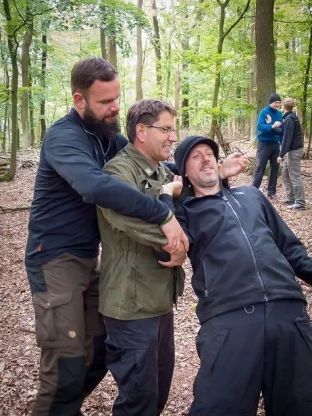 Drei Personen unterstützen sich gegenseitig in einem Waldgebiet