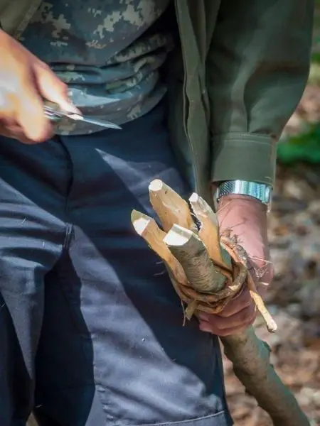 Ein Messer schneidet Holzstöcke, die in einer Hand gehalten werden