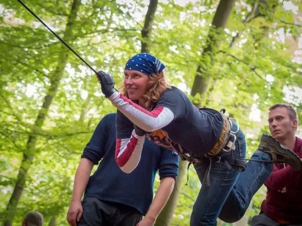 Frau überquert selbstgebaute Seilbrücke mit gesichertem Seil