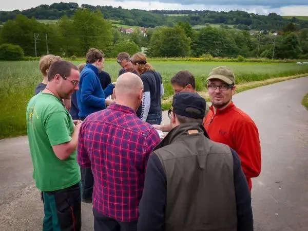 Gruppe betrachtet eine Karte auf einem Weg neben einem Feld