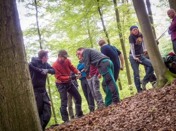 Gruppe von Personen zieht an einem Seil im Wald beim Überlebenstraining