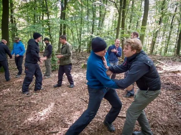 Gruppenteilnehmer üben in einem Wald körperliche Techniken