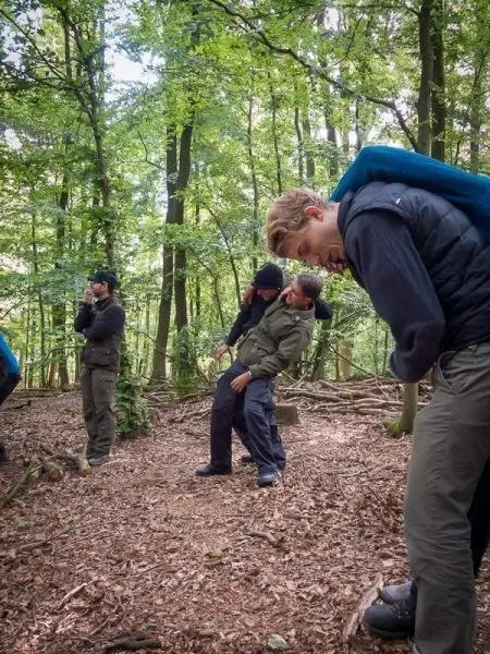 Gruppierung von Personen im Wald, einige stehen, andere lehnen sich aneinander