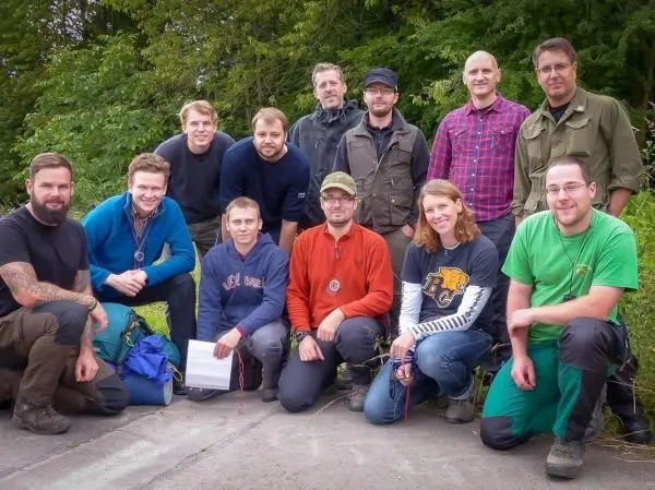 Gruppierung von zwölf Personen im Freien, einige halten Ausrüstung in den Händen