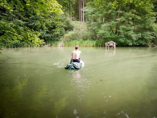 Junge paddelt auf improvisiertem Boot über einen stillen Teich