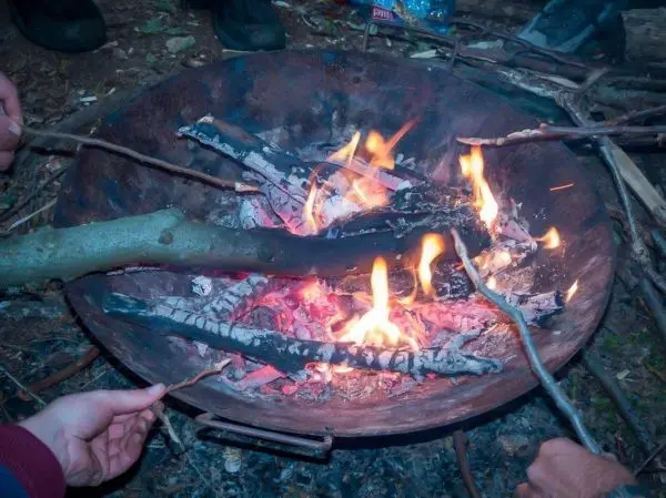 Kleine Flamme in einer Feuerstelle mit glühenden Holzstücken