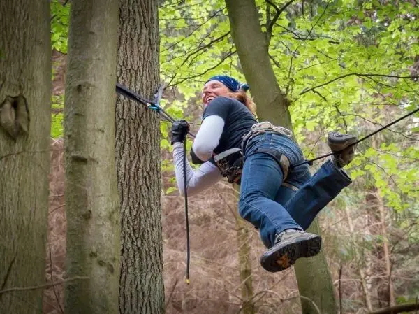 Kletterausrüstung wird an einem Baumstamm befestigt, während eine Person sich abseilt