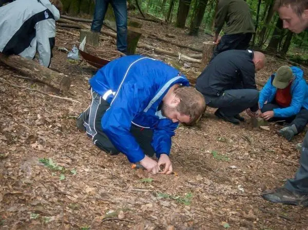 Mann bearbeitet den Boden mit einem Messer in einem Waldgebiet