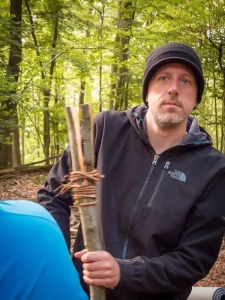 Mann hält gebündelte Äste in einem Waldgebiet