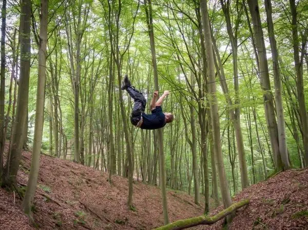 Mann überquert selbstgebaute Seilbrücke zwischen Bäumen im Wald