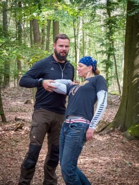 Mann unterstützt Frau mit verletztem Arm im Wald