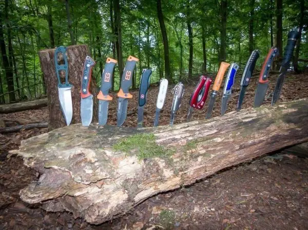 Mehrere Messer stehen auf einem umgefallenen Baumstamm im Wald