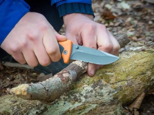 Messer schneidet Holzstück in einem Waldgebiet